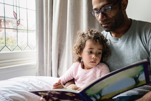 Father reading daughter a story book