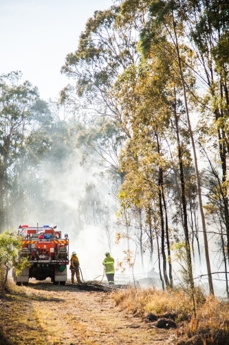 NSW rural fire service volunteer firefighter beside truck in fire smoke - Australian Stock Image