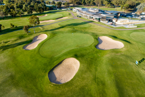 oblique aerial view of golf green with bunkers and clubhouse - Australian Stock Image
