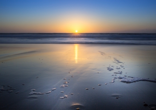 Ocean sunrise over wet sand