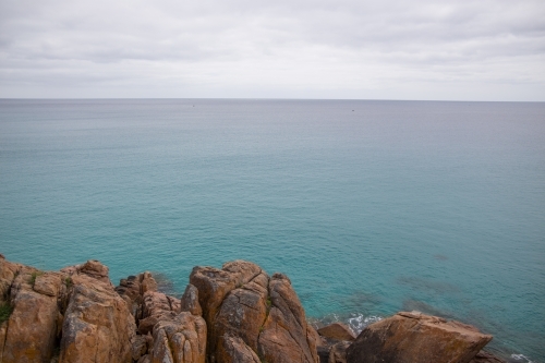 Ocean view with rocks in the foreground on overcast day - Australian Stock Image