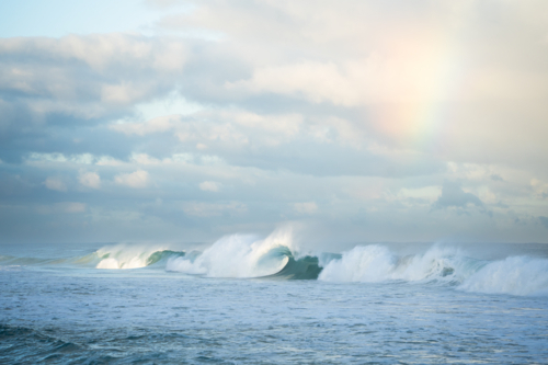 Ocean wave crashing with sun flare creating mist spray at Scarborough Beach, Perth - Australian Stock Image