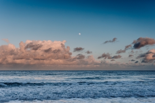 Ocean with pink clouds and moon