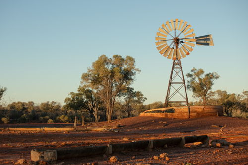 Old abandoned windmill and turkey nest with trough in the foreground - Australian Stock Image