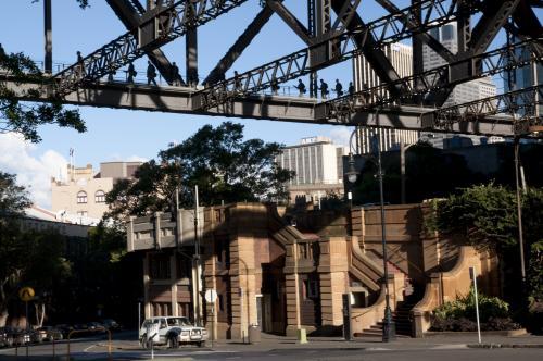 Old buildings viewed under iron girders of the Sydney Harbour Bridge with bridge climbers