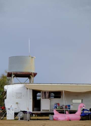 Old caravan and water tank behind retro flamingo