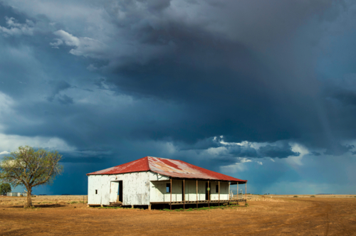 Old corrugated shed with a rusted roof beneath a brooding outback storm sky. - Australian Stock Image