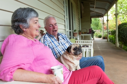 Old couple sitting on the front porch with their pet dog