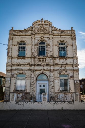 Old derelict building with weathered facade standing grand against a blue sky