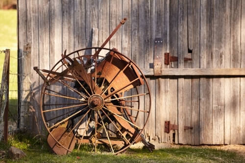 Old farm implement beside old farm building. - Australian Stock Image