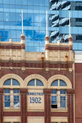 Old historic building with modern glass skyscraper behind - Australian Stock Image