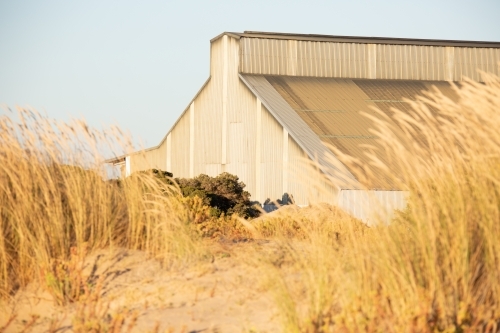 old industrial building at the port obscured in sand dunes - Australian Stock Image