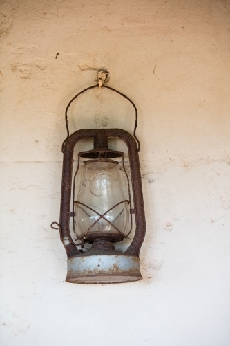 Old pioneer lantern hanging on a white stone wall