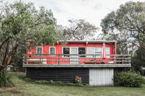 Old red beach shack with gum trees - Australian Stock Image