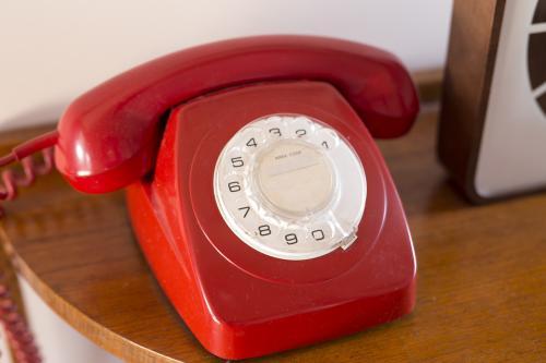 Old red rotary telephone on sideboard - Australian Stock Image
