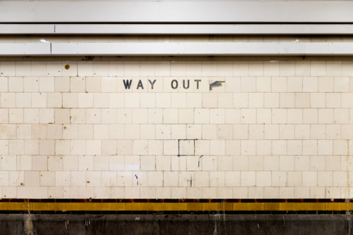 Old tiled wall with a weathered 'Way Out' sign in an underground train station - Australian Stock Image