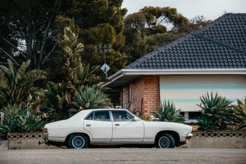 old vintage car parked in front of a brick house - Australian Stock Image