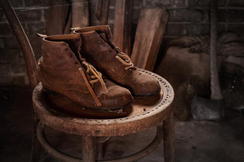Old workboots sitting on old chair. - Australian Stock Image