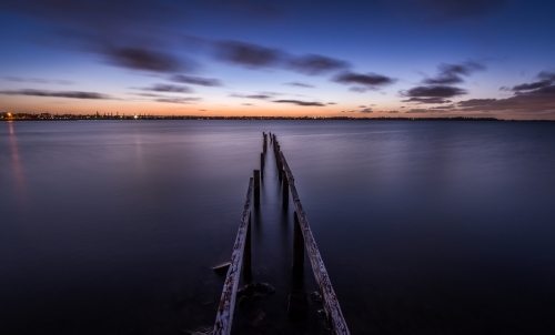 Old worn and weathered jetty leading into the sea at sunset