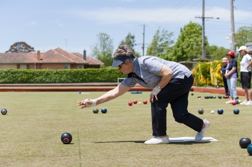 Older woman delivering a lawn bowl - Australian Stock Image
