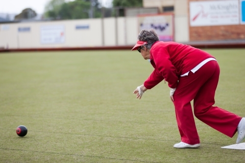 Older woman delivering a lawn bowl - Australian Stock Image