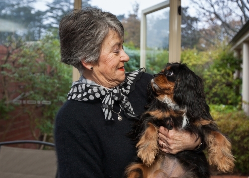 Older woman holding small dog at home