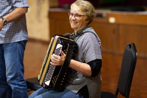 older woman seated playing accordion