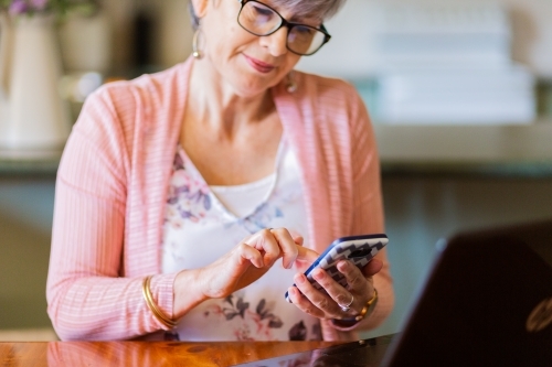Older woman using mobile phone typing with one finger - Australian Stock Image