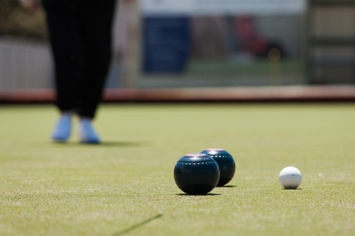 Older woman walking toward bowls and jack - Australian Stock Image