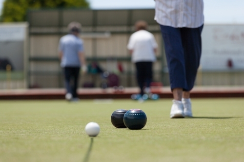 Older woman walking towards bowls and jack - Australian Stock Image
