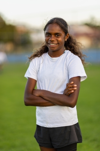 one aboriginal girl standing with arms crossed at the field - Australian Stock Image