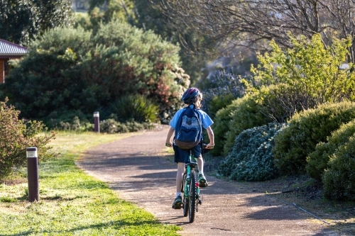 One child riding bike to school along path - Australian Stock Image