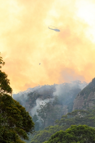 One fire fighting helicopter dumping water onto a bushfire on Maddens Plains, Illawarra, NSW - Australian Stock Image