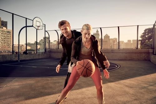 One on one basketball game played by a man and woman - Australian Stock Image