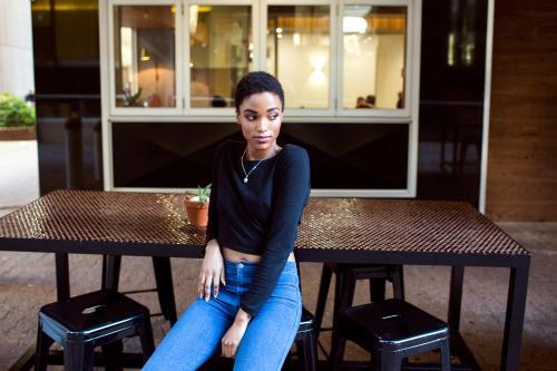 One stylish young woman sitting outside at a cafe table - Australian Stock Image