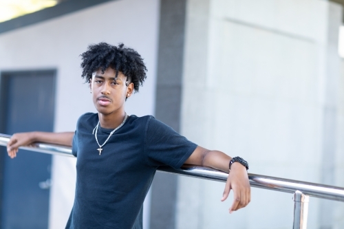one young man in black tee leaning against railing - Australian Stock Image