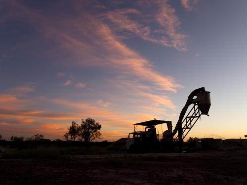 Opal extraction machinery silhouetted against sunset - Australian Stock Image