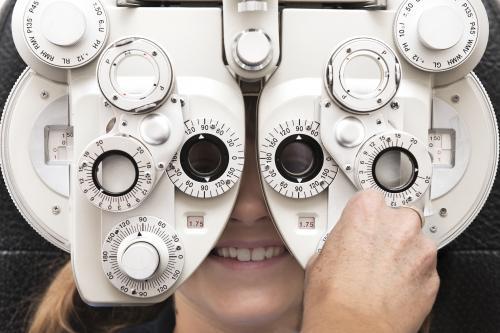 optometrist using a phoropter to measure a girl's eyesight - Australian Stock Image