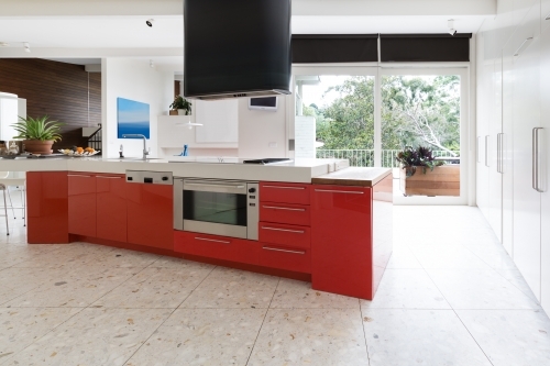 Orange kitchen cabinets in island bench in modern luxury home - Australian Stock Image