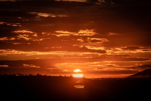 Orange sun setting over rural landscape - Australian Stock Image