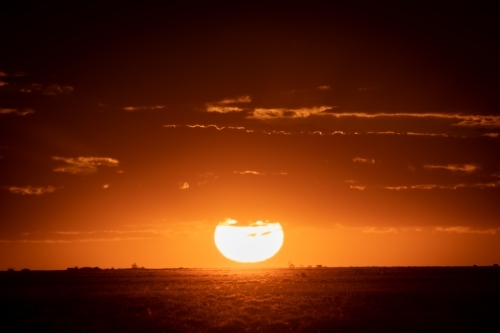 Orange sun setting over rural landscape - Australian Stock Image