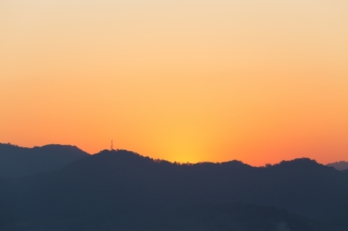 Orange sunset over distant rolling hills