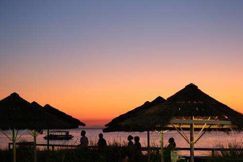 Orange sunset over thatched shelters on island - Australian Stock Image