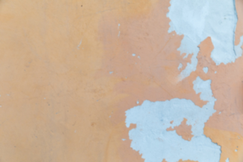 Out of focus no focus weathered orange ochre coloured render wall with Blue paint chips. - Australian Stock Image