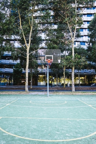 Outdoor basketball court in the city with apartment building in the background