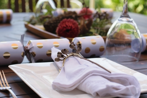 Outdoor Christmas table setting with native flowers and gold and white bon bon
