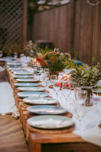 Outdoor dining setup with elegant tableware and seasonal flowers at sunset - Australian Stock Image