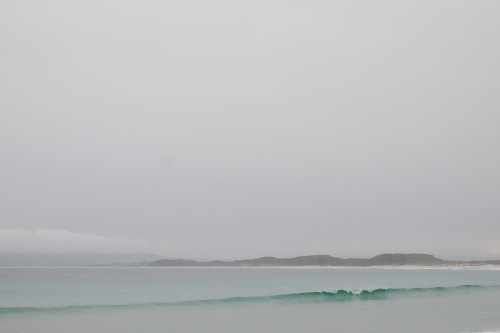 Overcast seascape with single wave crashing along remote deserted coastline - Australian Stock Image
