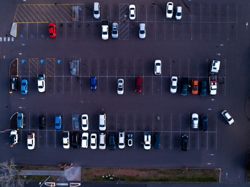 Overhead aerial view of cars parked in bays in half empty car park