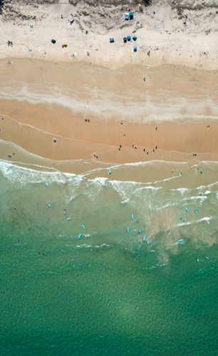Overhead aerial view of young surfers learning to surf on australian beach - Australian Stock Image
